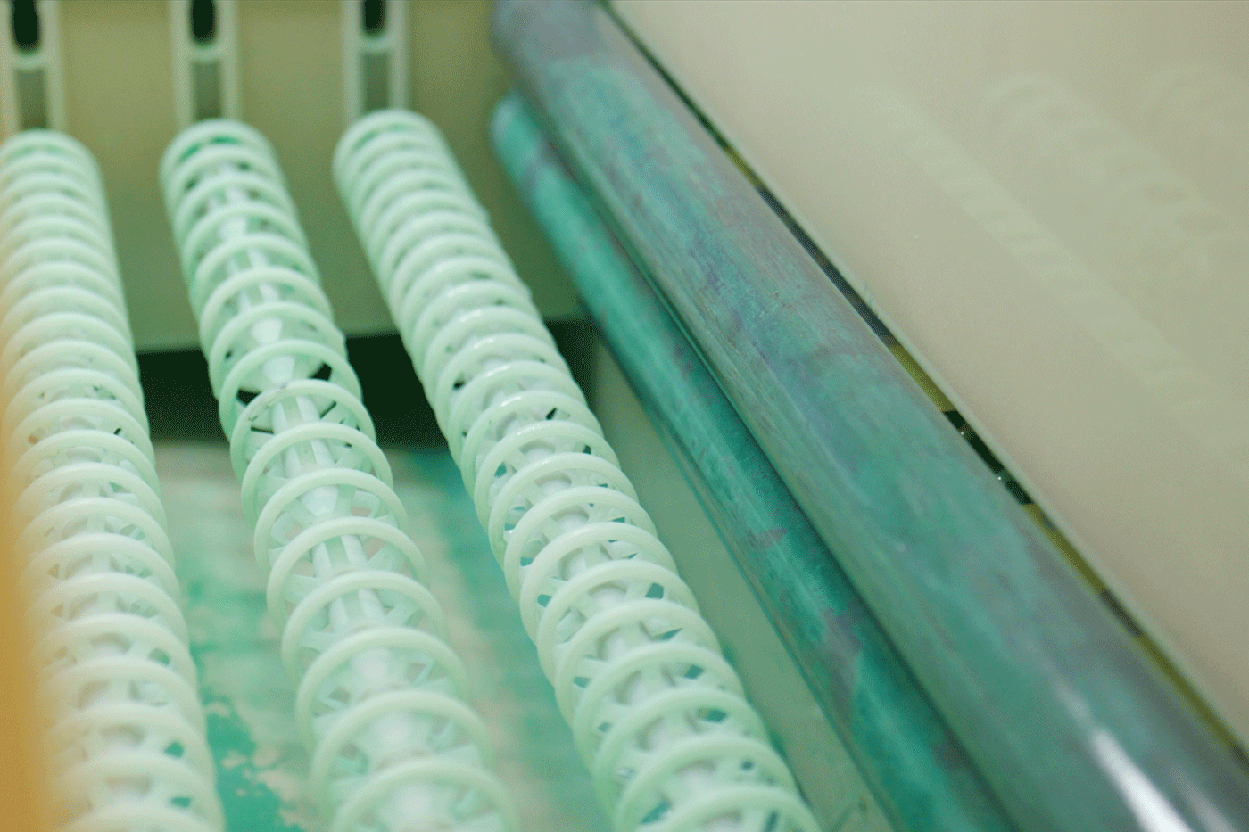 Spiral anodes are immersed in a chrome bath within electroplating equipment, facilitating the chrome plating process on metal parts in an industrial setting
