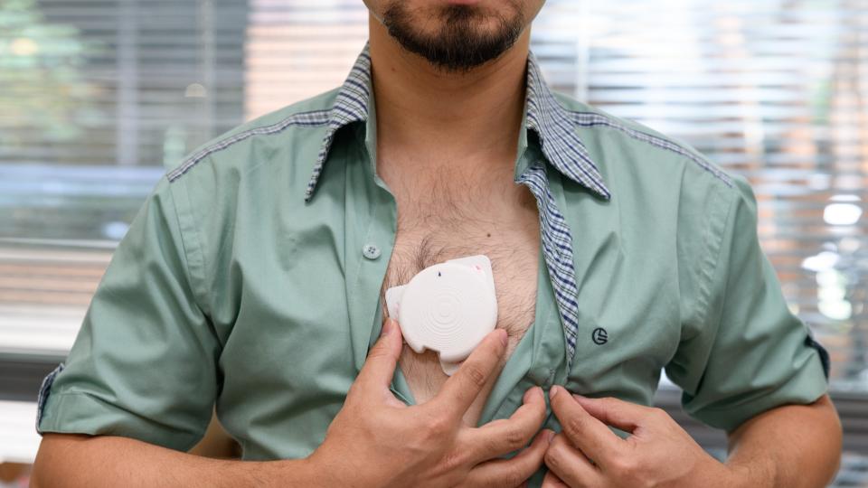 man baring chest an holding a patch against his skin